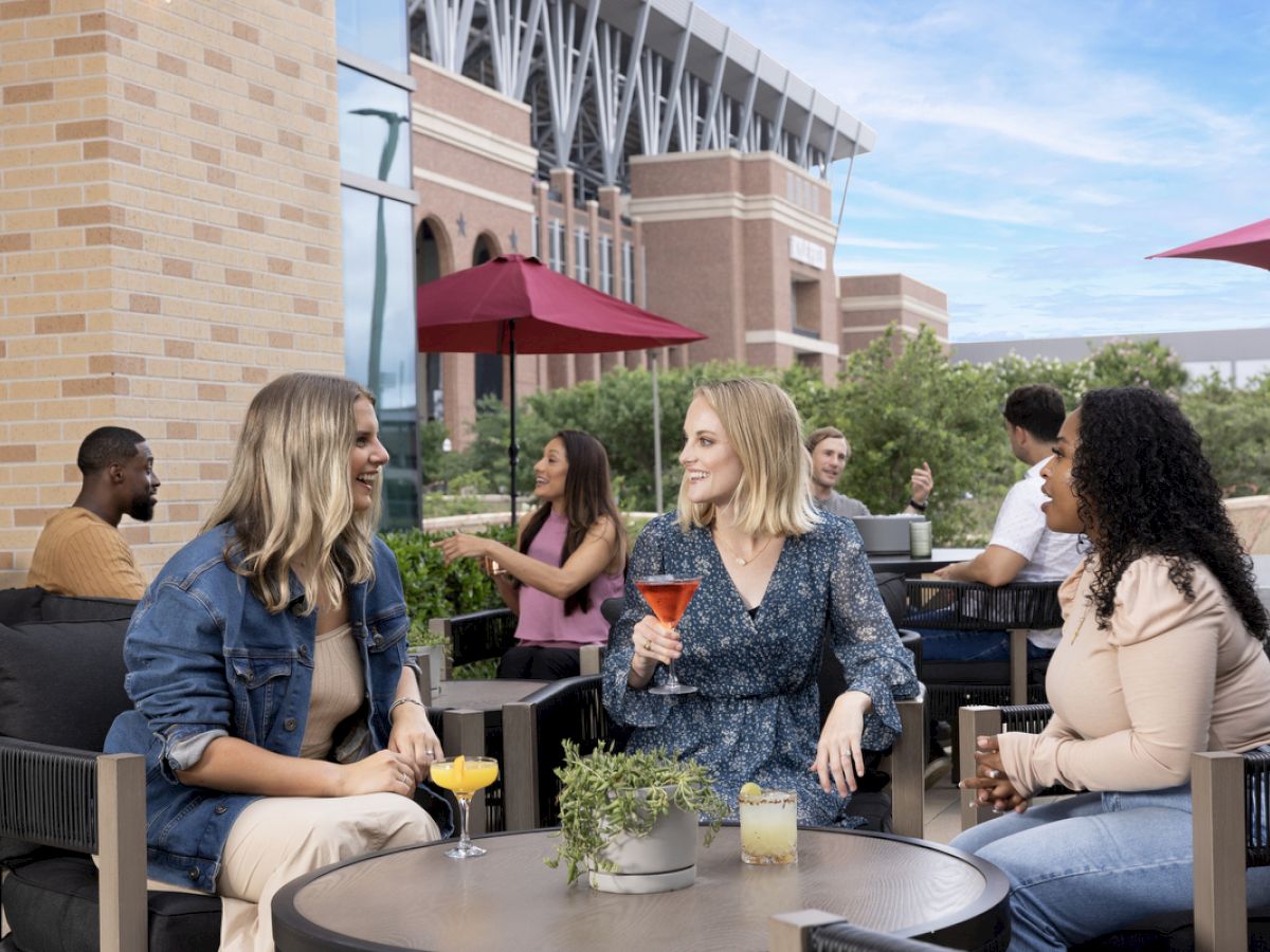 group of 3 girls enjoying drinks on patio of The Rail overlooking Kyle Field