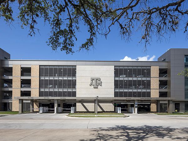 A modern university building facade with &ldquo;A&M&rdquo; signage and glass windows under a blue sky.