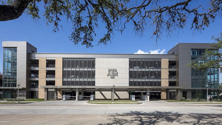 A modern university building facade with &ldquo;A&M&rdquo; signage and glass windows under a blue sky.