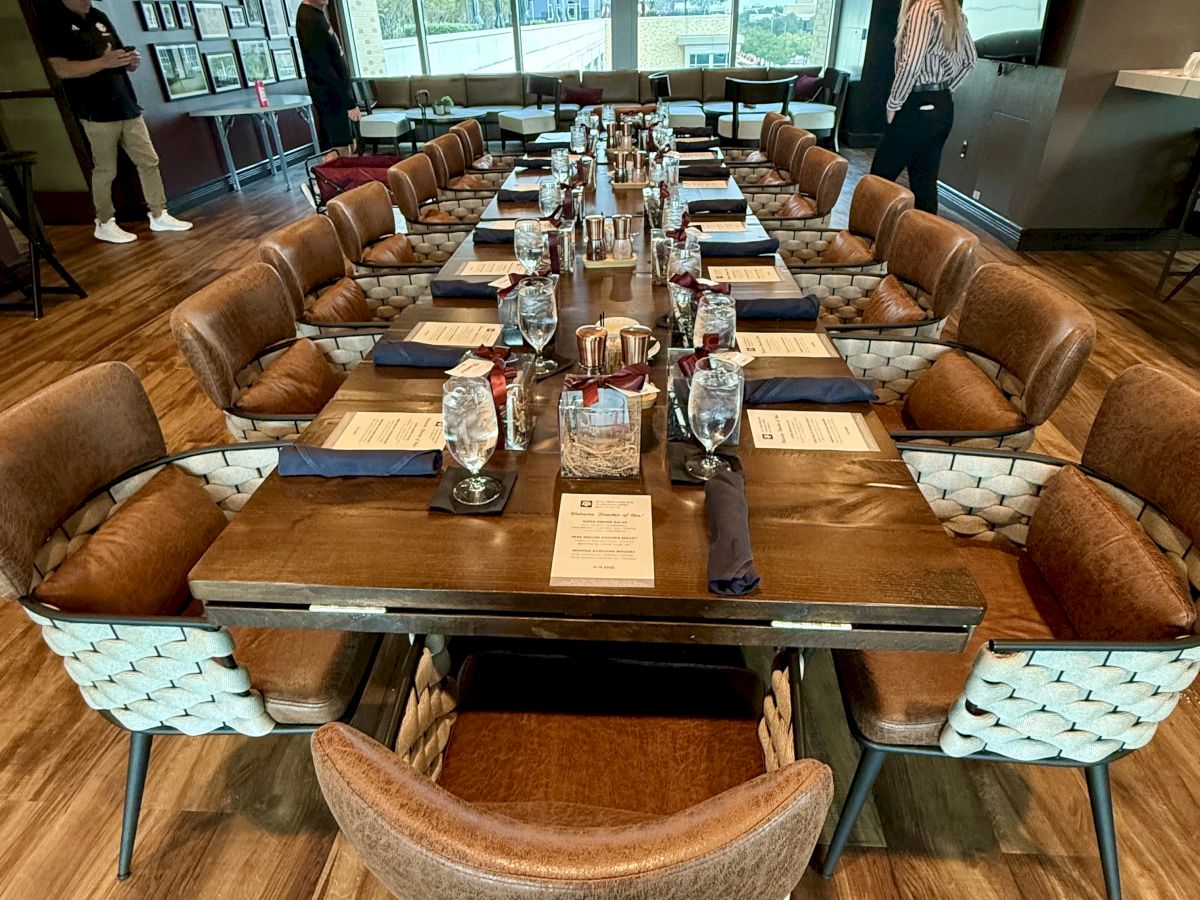 A styled meeting room set for a meal, with brown booths, a central table of drinks, menus, and pendant lights.