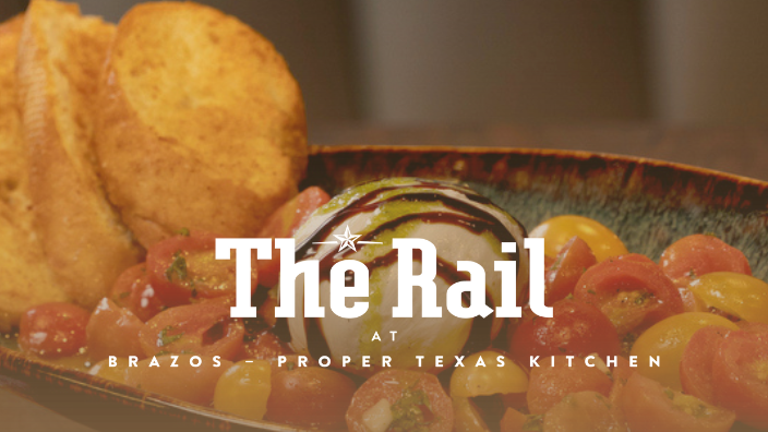 A dish with sliced tomatoes and an onion, garnished with toasted bread, and the text "The Rail" in front.