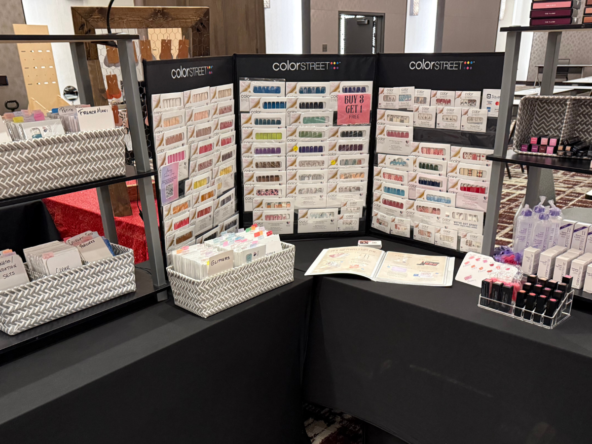 A display of Color Street nail products featuring various nail polish strips, accessories, and promotional materials on a black table.